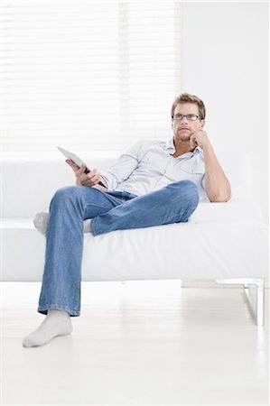 simsearch:6108-06904945,k - Man watching television on couch Stock Photo - Premium Royalty-Free, Code: 6122-08229125