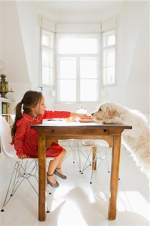 pets sharing food - Girl feeding dog at table Stock Photo - Premium Royalty-Free, Code: 6122-08229581