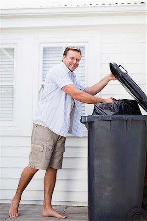 dustbin with waste material - Smiling man taking out garbage Stock Photo - Premium Royalty-Free, Code: 6122-08229873