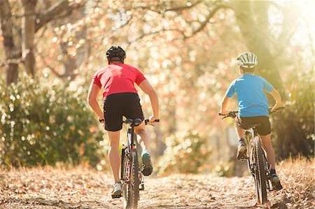 Father and son mountain biking on path in woods Stock Photo - Premium Royalty-Free, Code: 6124-08170421