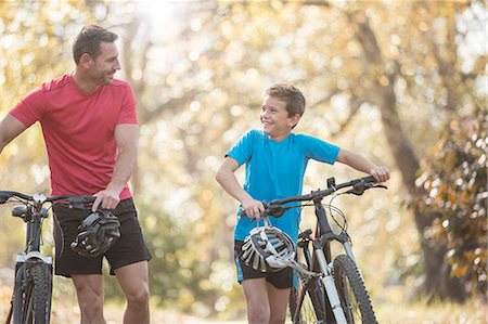 Father and son walking mountain bikes in woods Stock Photo - Premium Royalty-Free, Code: 6124-08170430
