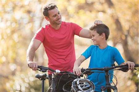 family mountain bike - Affectionate father and son with mountain bikes outdoors Stock Photo - Premium Royalty-Free, Code: 6124-08170435