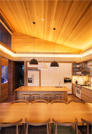 Illuminated slanted wood ceiling over luxury kitchen and dining table Stock Photo - Premium Royalty-Free, Code: 6124-08170703