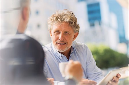 Businessmen drinking coffee using digital tablet at urban sidewalk cafe Stock Photo - Premium Royalty-Free, Code: 6124-08743186