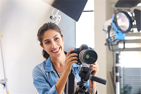 equipment - Smiling female photographer behind camera in studio Stock Photo - Premium Royalty-Free, Code: 6124-08743242