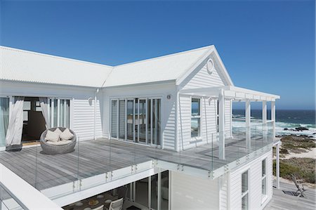 simsearch:6124-08703974,k - White beach house with balcony with ocean view under sunny blue sky Stock Photo - Premium Royalty-Free, Code: 6124-08703847