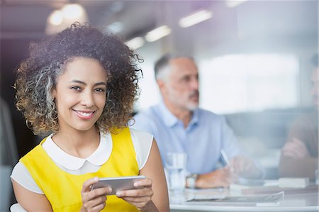 simsearch:6108-06907863,k - Portrait smiling businesswoman texting with cell phone in meeting Stock Photo - Premium Royalty-Free, Code: 6124-08703880