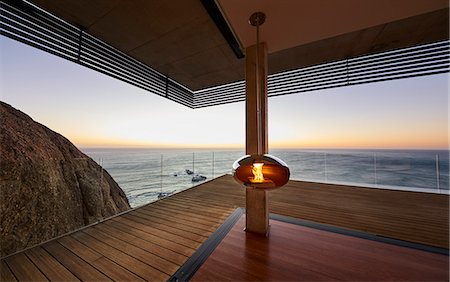 simsearch:6124-08703974,k - Modern hanging fireplace on luxury beach house patio with sunset ocean view Stock Photo - Premium Royalty-Free, Code: 6124-08703976