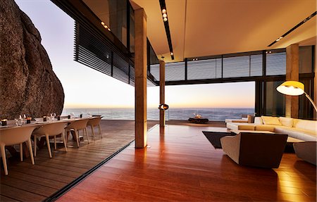 simsearch:6124-08703974,k - Modern luxury living room open to patio with sunset ocean view Stock Photo - Premium Royalty-Free, Code: 6124-08703999