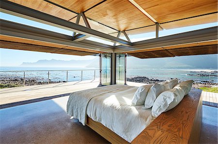 simsearch:6124-08703974,k - Modern luxury bed open to patio with sunny ocean view Stock Photo - Premium Royalty-Free, Code: 6124-08704035