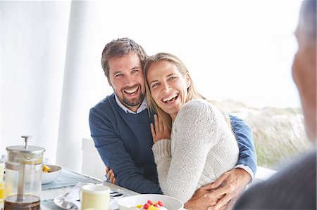 Happy affectionate couple laughing and hugging at patio breakfast Stock Photo - Premium Royalty-Free, Code: 6124-08805219