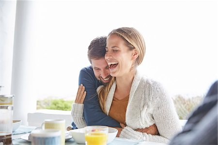 simsearch:6113-06720867,k - Affectionate couple hugging and laughing at breakfast on patio Stock Photo - Premium Royalty-Free, Code: 6124-08805237