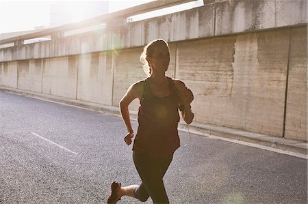 exercises for fit women - Silhouette female runner running on sunny urban street Stock Photo - Premium Royalty-Free, Code: 6124-08820858