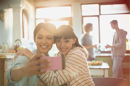 simsearch:6113-06908601,k - Young women friends roommates hugging taking selfie with camera phone Stock Photo - Premium Royalty-Free, Code: 6124-08821052
