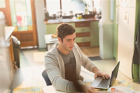 simsearch:6113-07730780,k - Young man college student studying at laptop in kitchen Stock Photo - Premium Royalty-Free, Code: 6124-08821026