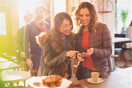simsearch:6113-08743448,k - Women friends using cell phone in cafe Stock Photo - Premium Royalty-Free, Code: 6124-08946007