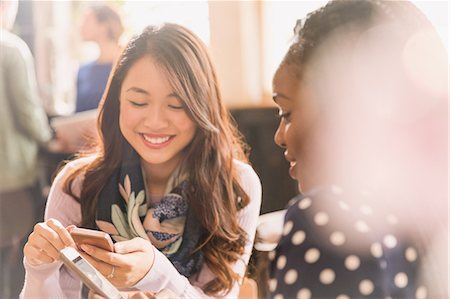 simsearch:6113-08743448,k - Female friends texting with cell phones in cafe Stock Photo - Premium Royalty-Free, Code: 6124-08946005