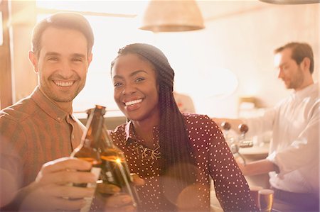 simsearch:6113-07565751,k - Portrait smiling couple toasting beer bottles in bar Stock Photo - Premium Royalty-Free, Code: 6124-08946104