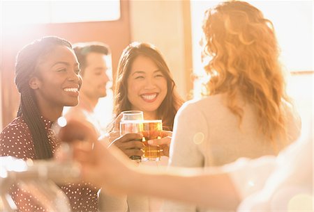 simsearch:6113-07147381,k - Smiling women friends toasting beer glasses in sunny bar Stock Photo - Premium Royalty-Free, Code: 6124-08946110