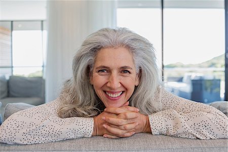 Portrait happy mature woman leaning over sofa in living room Photographie de stock - Premium Libres de Droits, Code: 6124-08907876