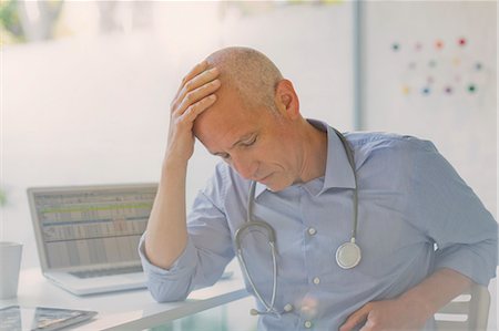 daytime fatigue - Tired, stressed male doctor with head in hands in doctor’s office Foto de stock - Sin royalties Premium, Código: 6124-08908082