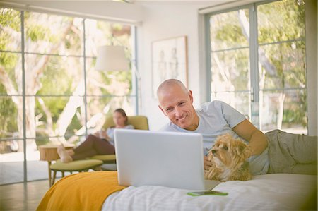 simsearch:6113-06753677,k - Smiling man with dog using laptop on bed Stock Photo - Premium Royalty-Free, Code: 6124-08908025