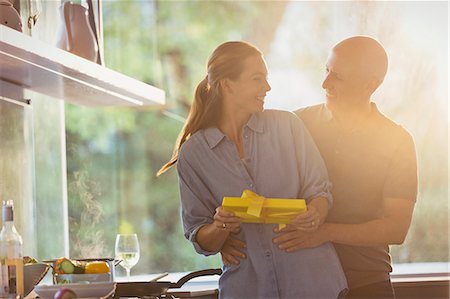 simsearch:6113-07790692,k - Smiling husband surprising wife with gift in sunny kitchen Stock Photo - Premium Royalty-Free, Code: 6124-08908140