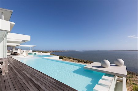 simsearch:6113-07147822,k - Sunny, tranquil modern luxury home showcase exterior infinity pool with ocean view under blue sky Photographie de stock - Premium Libres de Droits, Code: 6124-08908152