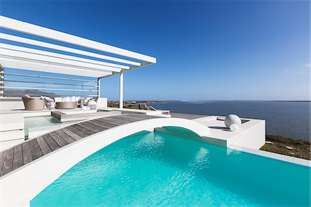 simsearch:6113-07147822,k - Sunny tranquil home showcase exterior infinity pool with ocean view under blue sky Photographie de stock - Premium Libres de Droits, Code: 6124-08908170