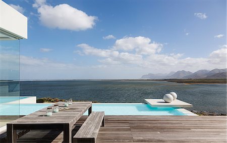 simsearch:6124-08703974,k - Sunny tranquil modern luxury patio with infinity pool and ocean view Stock Photo - Premium Royalty-Free, Code: 6124-08908193