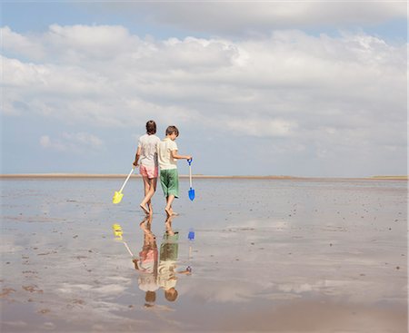simsearch:649-07761212,k - Brother and sister walking with shovels in wet sand on sunny summer beach Stock Photo - Premium Royalty-Free, Code: 6124-08908269