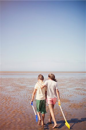 simsearch:649-08004031,k - Brother and sister with shovels hugging and walking in wet sand on sunny summer beach below blue sky Stock Photo - Premium Royalty-Free, Code: 6124-08908273