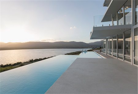 simsearch:6124-08703974,k - Sunny, tranquil modern luxury home showcase exterior with infinity pool and sunset ocean view Stock Photo - Premium Royalty-Free, Code: 6124-08908225