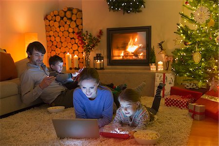 fireplace - Family relaxing, using laptop, digital tablet and cell phone in ambient Christmas living room Stock Photo - Premium Royalty-Free, Code: 6124-08926897