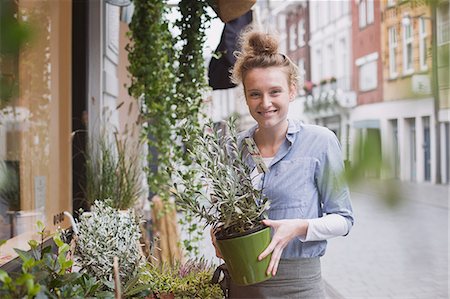 service in supermarket - Portrait smiling female florist holding potted plant at storefront Stock Photo - Premium Royalty-Free, Code: 6124-08926811