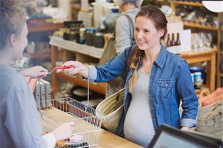 simsearch:400-04106195,k - Pregnant woman giving basket to cashier at checkout counter in shop Stock Photo - Premium Royalty-Free, Code: 6124-08926839