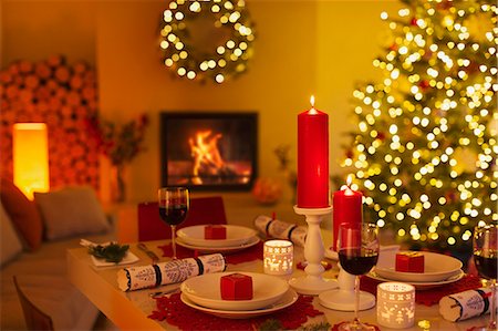 Ambient candles and Christmas crackers on dinner table in living room with fireplace and Christmas tree Stock Photo - Premium Royalty-Free, Code: 6124-08926986