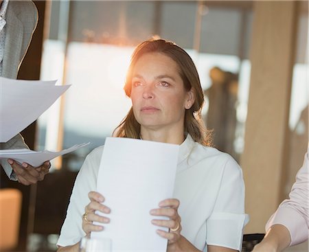 simsearch:649-07119200,k - Serious, pensive businesswoman with paperwork looking away in office Stock Photo - Premium Royalty-Free, Code: 6124-09056443
