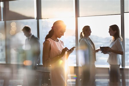 sending - Businesswoman texting with cell phone in sunny conference room Stock Photo - Premium Royalty-Free, Code: 6124-09056402