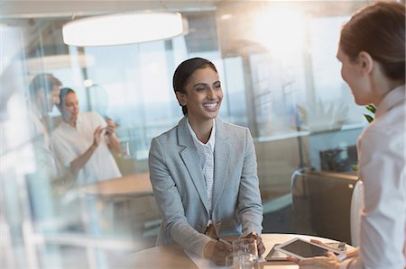 Smiling businesswomen talking, using digital tablet in conference room meeting Stock Photo - Premium Royalty-Free, Code: 6124-09056423