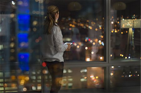 simsearch:649-07119200,k - Pensive businesswoman with digital tablet working late, looking out urban office window at night Stock Photo - Premium Royalty-Free, Code: 6124-09056436