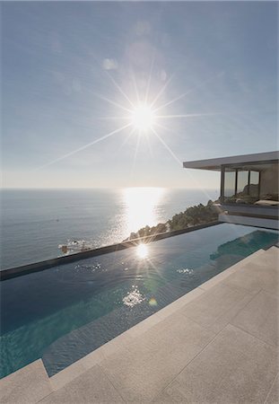 simsearch:6124-08703974,k - View of sun shining over ocean and modern, luxury home showcase exterior lap pool patio Stock Photo - Premium Royalty-Free, Code: 6124-09099781