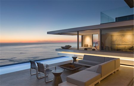 simsearch:6113-07159869,k - Illuminated modern, luxury home showcase exterior patio with sofa and lap pool with ocean view at dusk Stock Photo - Premium Royalty-Free, Code: 6124-09099853