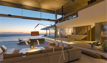 simsearch:6124-08703974,k - Illuminated modern, luxury home showcase interior living room with ocean view at dusk Stock Photo - Premium Royalty-Free, Code: 6124-09099863