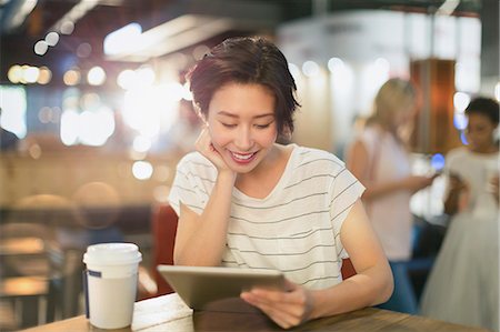 simsearch:614-02985269,k - Young woman using digital tablet and drinking coffee in cafe Stock Photo - Premium Royalty-Free, Code: 6124-09004863