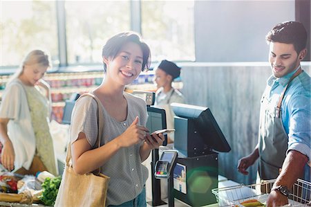 purchase groceries - Portrait smiling young woman at grocery store checkout Stock Photo - Premium Royalty-Free, Code: 6124-09004892