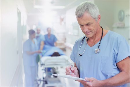 simsearch:632-01613036,k - Mature male surgeon reviewing medical record clipboard in hospital corridor Stock Photo - Premium Royalty-Free, Code: 6124-09026343