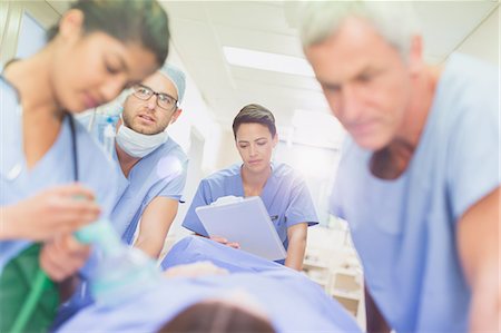 simsearch:6113-07762019,k - Surgeons with clipboard pushing patient on stretcher in hospital corridor Stock Photo - Premium Royalty-Free, Code: 6124-09026351