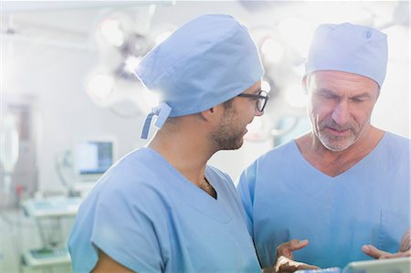 simsearch:649-07064718,k - Male surgeons talking, using digital tablet in operating room Stock Photo - Premium Royalty-Free, Code: 6124-09026371