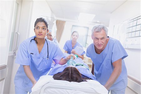 surgical gown - Determined surgeons pushing female patient on stretcher down hospital corridor Photographie de stock - Premium Libres de Droits, Code: 6124-09026328